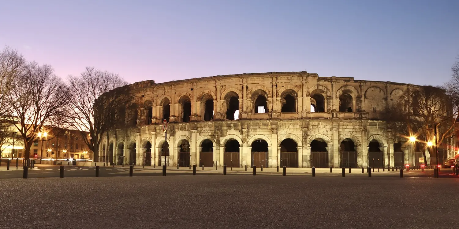 Les arènes de Nîmes éclairées au crépuscule, ville où intervient VMDA Web